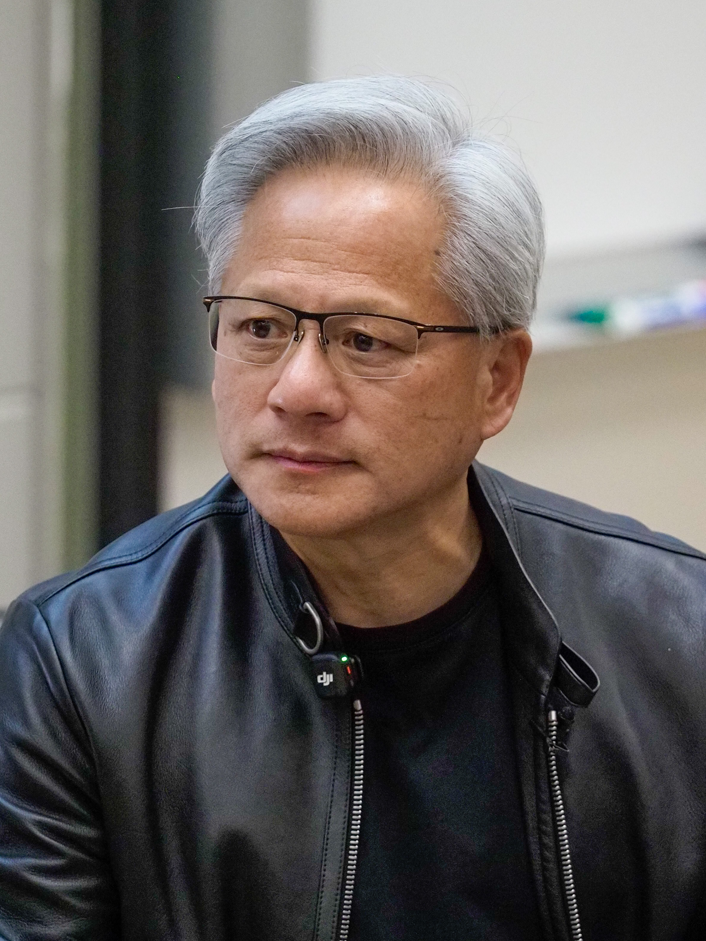 Jensen Huang listening at Stanford University on April 30, 2026, wearing a black leather jacket. This event portrait predates his September AGI statement.